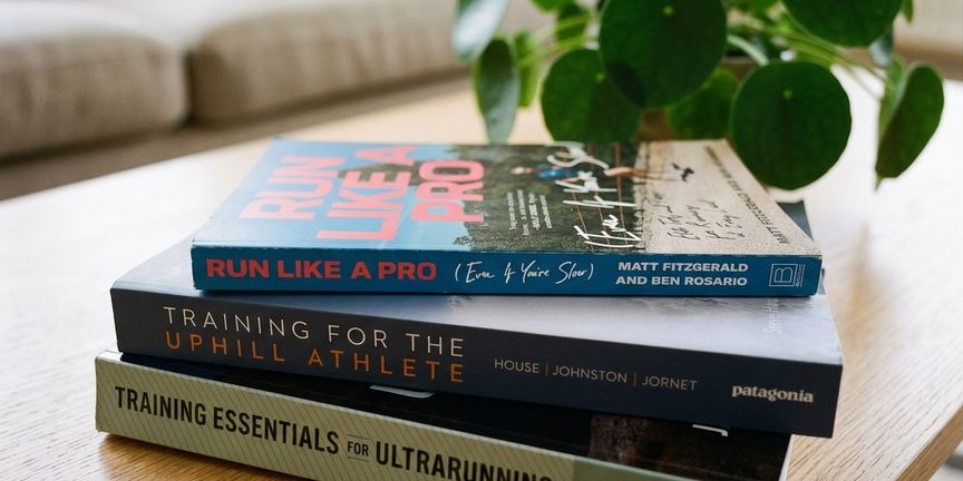Stapel hardloopboeken over training op een tafel, met een kamerplant op de achtergrond