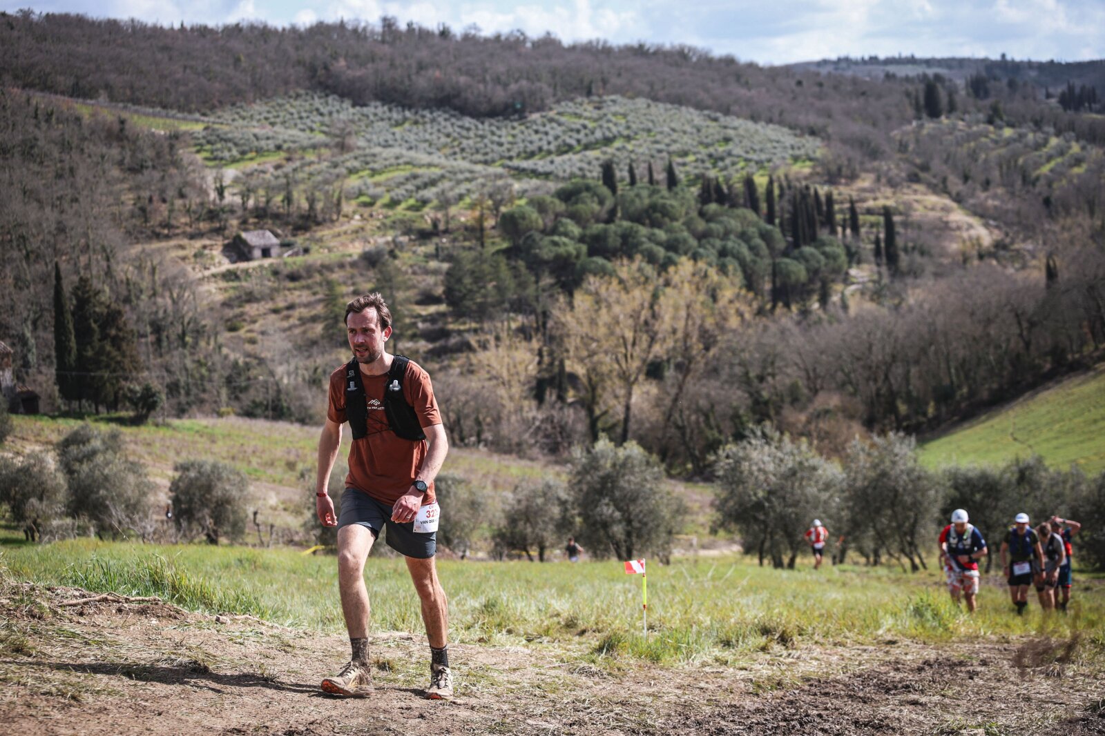 Hardloper met wedstrijdnummer klimt door de Chianti-heuvels tijdens een trailrace